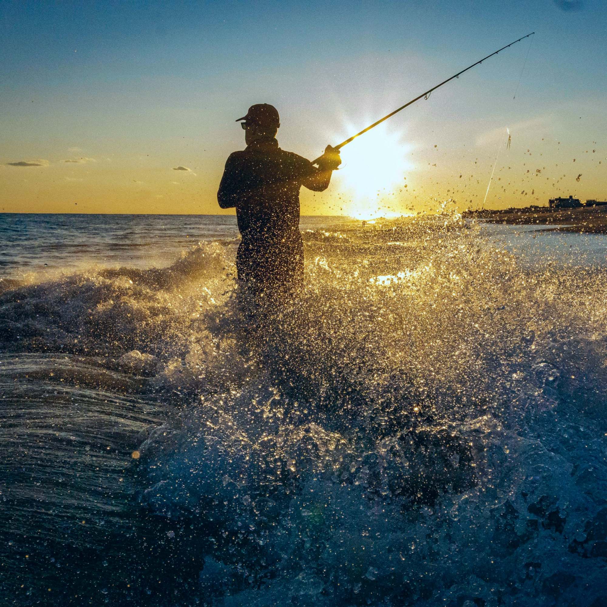 Angler casting into breaking surf at sunrise